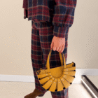 Bolso Abanico Soleil de piel italiana en mostaza llevado de la mano con pantalón de cuadros