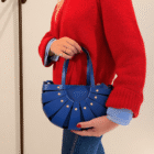 Detalle del Bolso Abanico Soleil azul klein con remaches dorados, llevado al brazo