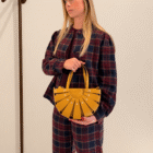 Mujer con camisa y pantalón de cuadros llevando el Bolso Abanico Soleil en mostaza