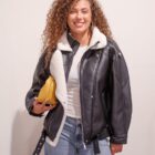 Cazadora Bowie de cuero negro y borreguito, abierta sobre camiseta blanca y vaqueros