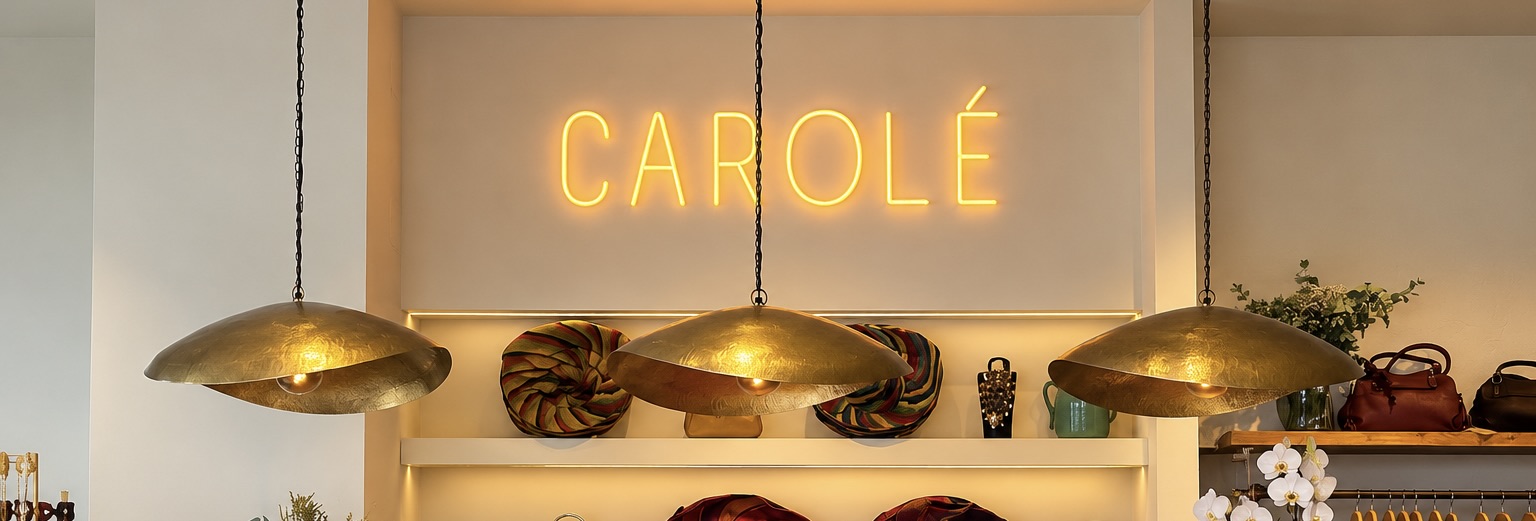 Interior de la tienda Carolé en Suances con el rótulo luminoso y bolsos expuestos