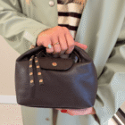 Bolso Media Luna de piel italiana en marrón chocolate llevado de la mano con gabardina verde agua