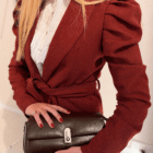 Bolso Dakota en marrón metalizado sujeto con las manos sobre blazer rojo