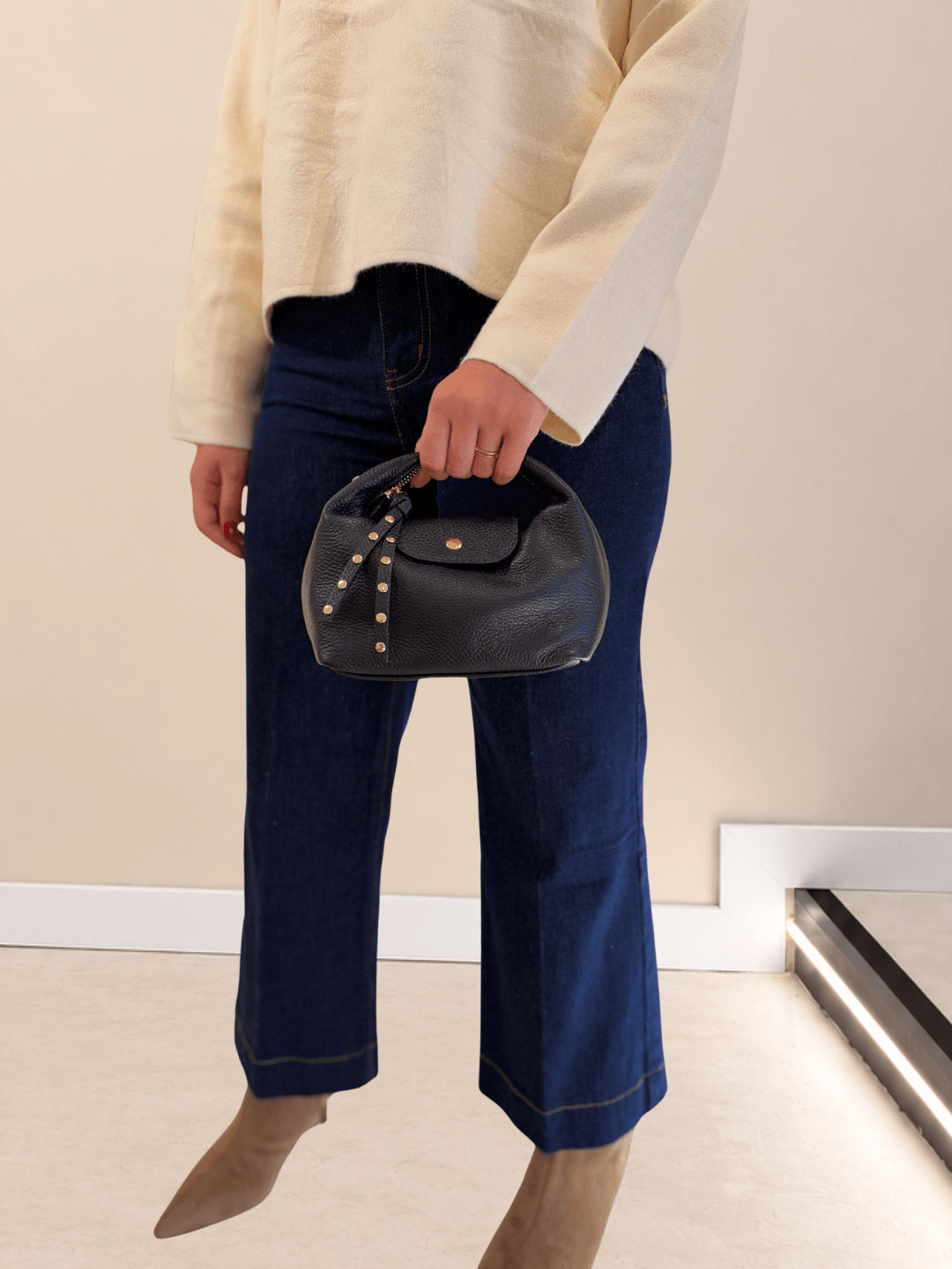 Bolso Media Luna de piel italiana azul marino colgado de la mano con vaqueros culotte