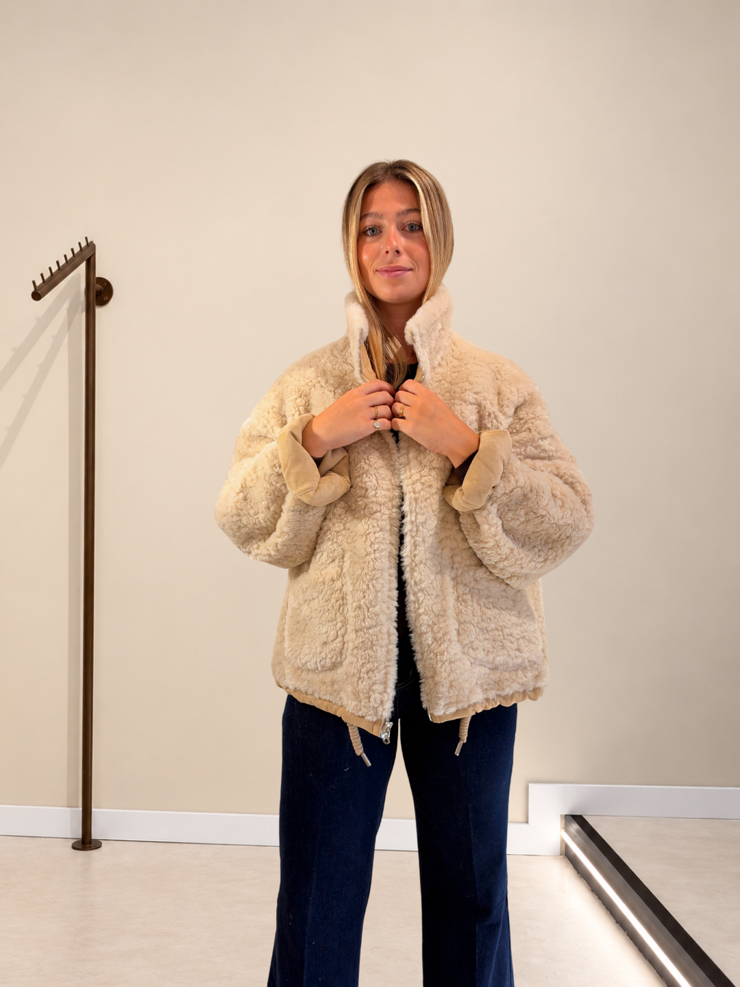 Abrigo Dakota reversible beige de pelo abrochándose el cuello